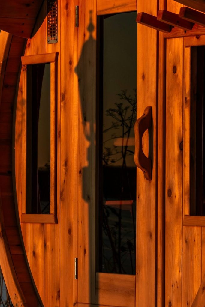 End wall of a cedar barrel sauna with a glazed door