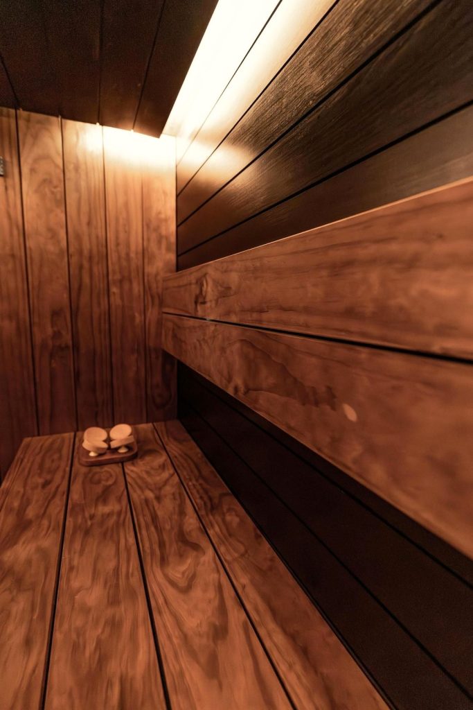 Dark cedar sauna room with lighting tucked under the upper bench