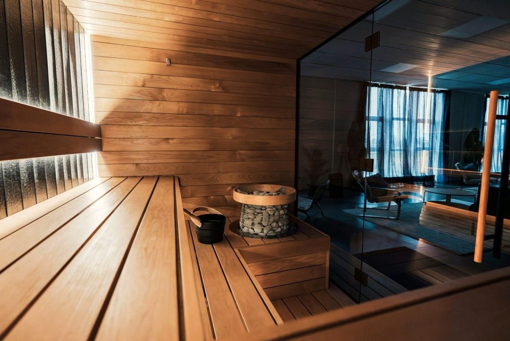 Home sauna in Napa with cedar benches, an electric heater and a glass front wall