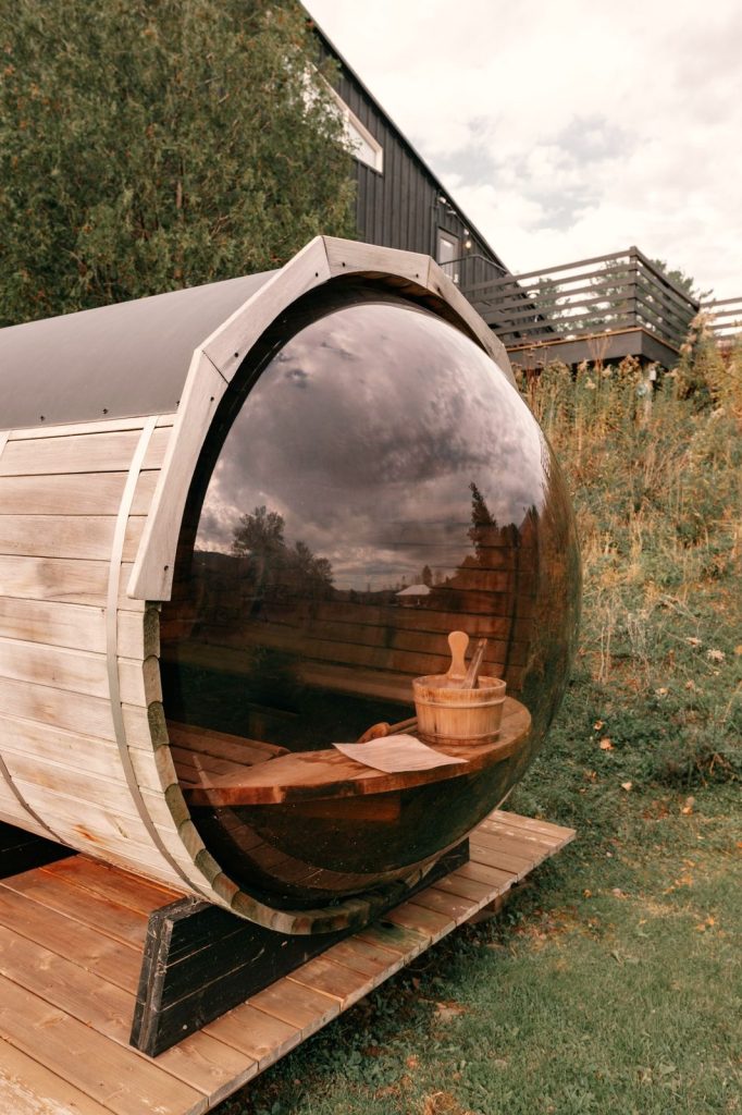 Barrel sauna with a curved glass end in an open field